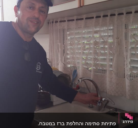 אדם ליד כיור מטבח עם ברז חדש